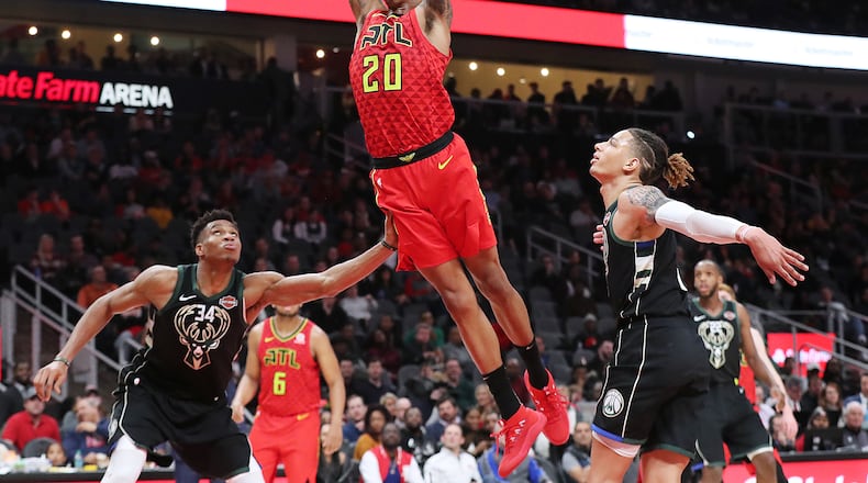 Hawks forward John Collins soars to the basket over the Bucks' Giannis Antetokounmpo. Curtis Compton/ccompton@ajc.com