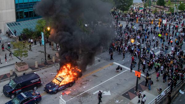 An Atlanta Police Department patrol car is engulfed in flames after demonstrators set it ablaze and destroyed other patrol cars outside the CNN Center in Atlanta on May 29, 2020. Following a peaceful march to the Georgia State Capitol to protest racial injustice and police brutality, demonstrators returned to the area around Centennial Olympic Park and CNN center and clashed with police. (ALYSSA POINTER / ALYSSA.POINTER@AJC.COM)