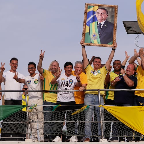 Opposition presidential candidate Flavio Bolsonaro holds a photo of his father, former President Jair Bolsonaro, as he rides a boat during a campaign rally ahead of the October general elections in Angra dos Reis, Rio de Janeiro state, Brazil, Saturday, Aug. 29, 2026. (AP Photo/Bruna Prado)