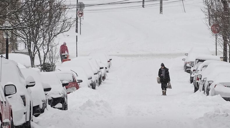 A person carries grocery bags up a residential street during a winter storm Sunday, Jan. 25, 2026, in Cincinnati. (AP Photo/Joshua A. Bickel)