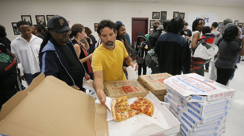 Angel Poventud, who voted early, volunteers his time to hand out pizza and snacks to people waiting in line. The wait time to vote at the Pittman Park precinct in Atlanta was reported to be three hours. Pizza and snacks were donated for the people waiting in line. BOB ANDRES / BANDRES@AJC.COM