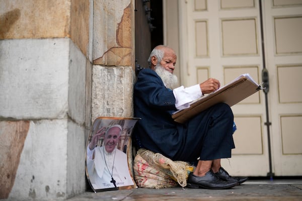 Oscar Gomez a street artist waits outside the Cathedral for a mass in tribute to the late Pope Francis in Bogota, Colombia, Saturday, April 26, 2025. (AP Photo/Fernando Vergara)