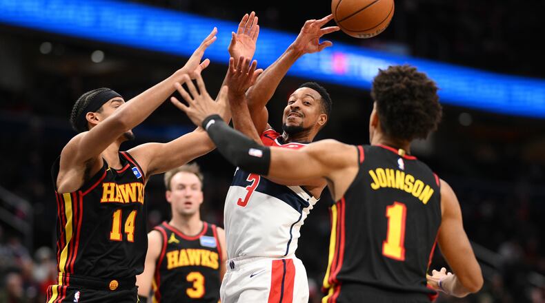 Washington Wizards guard CJ McCollum (3) passes the ball against Atlanta Hawks forward Asa Newell (14), forward Jalen Johnson (1) and guard Luke Kennard (3) during the first half of an NBA basketball game, Saturday, Dec. 6, 2025, in Washington. (AP Photo/Nick Wass)