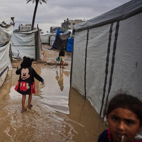 Palestinians walk through a flooded temporary tent camp after heavy rainfall in Deir al-Balah, central Gaza Strip, Tuesday, Nov. 25, 2025. (AP Photo/Abdel Kareem Hana)