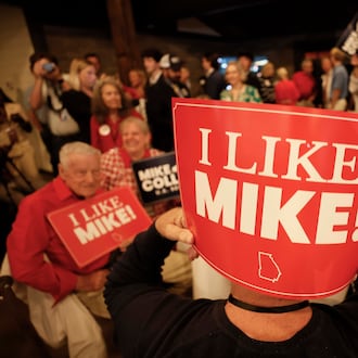 Supporters of U.S. Rep. Mike Collins hold banners as they watch him arrive on stage for his speech during the runoff election watch party in Jackson last month. (Miguel Martinez/AJC)