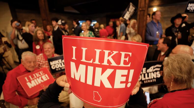 Supporters of U.S. Rep. Mike Collins hold banners as they watch him arrive on stage for his speech during the runoff election watch party in Jackson last month. (Miguel Martinez/AJC)