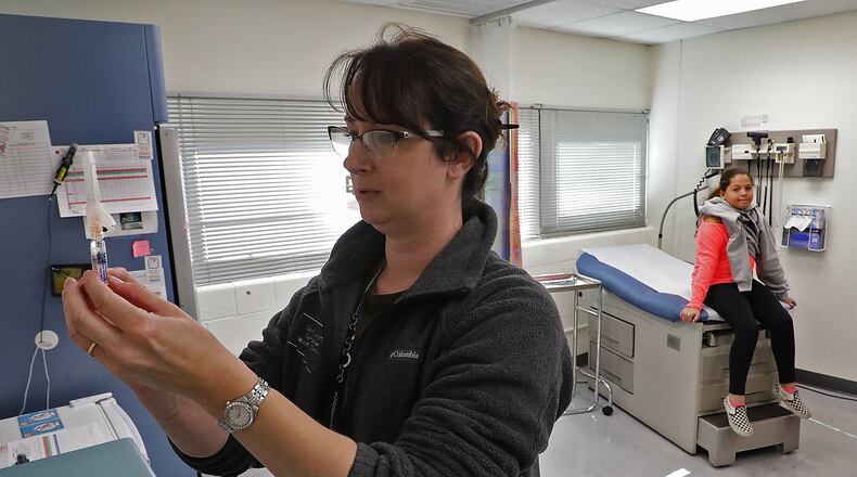 Kristen Earley, a nurse at the Clark County Combined Health District, gets a flu shot ready for Braylinne Muhammad, 11, at the Health District offices. BILL LACKEY/STAFF