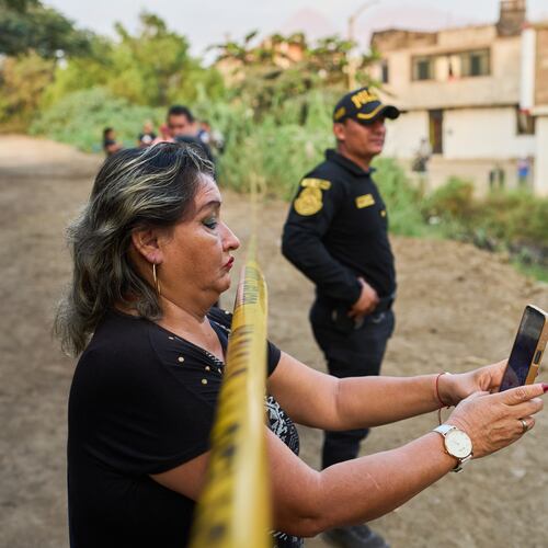 A neighbor records the scene with a cellphone as police recover the body of Jose Perez from a ravine where he was found shot in Trujillo, Peru, Friday, May 30, 2026. (AP Photo/Rodrigo Abd)