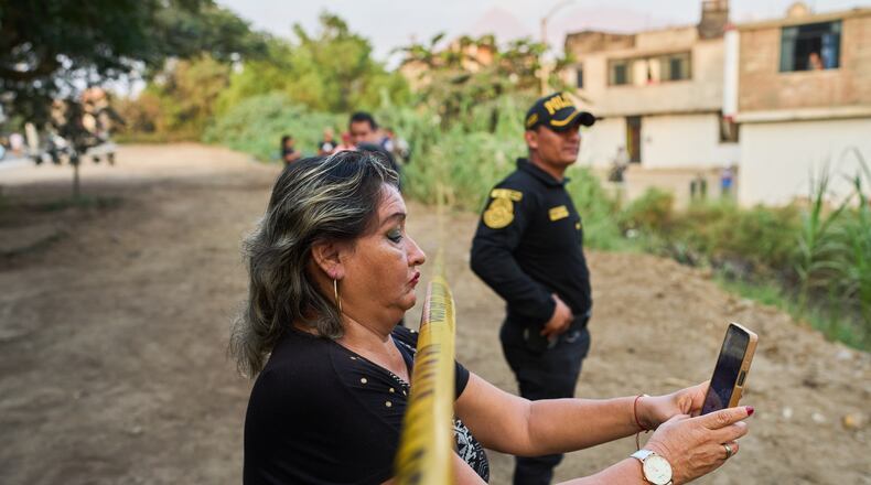 A neighbor records the scene with a cellphone as police recover the body of Jose Perez from a ravine where he was found shot in Trujillo, Peru, Friday, May 30, 2026. (AP Photo/Rodrigo Abd)