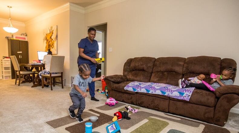 Basia Taylor balances her work as a dental hygienist, with one more exam to take, and her 2-year-old twins Michael, left, and Milani Blair, right, on Wednesday, April 7, 2021 at the apartment she shares with the twin's father and her mother, who works from home, for now. The family has adjusted through the pandemic with adjustments for child care, Taylor's education requirements and job schedules. (Jenni Girtman for The Atlanta Journal-Constitution)
