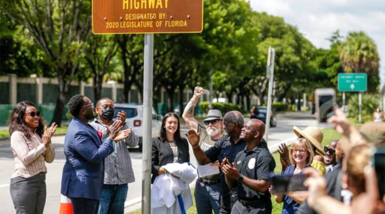 Isabella Banos, center, of the Harriet Tubman Highway Committee, joined by her grandfather, Modesto Abety, and local elected officials, smiles after unveiling the new sign renaming a portion of South Florida’s Dixie Highway after Harriet Tubman on Sept. 18.