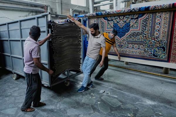 Indian workers push a cart loaded with carpets at a factory on the outskirts of Jammu, India, Tuesday, April 8, 2025. (AP Photo/Channi Anand)