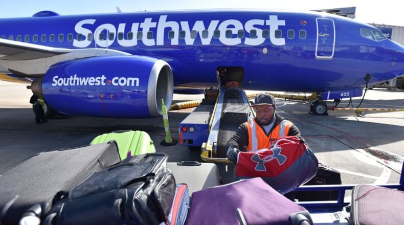Ramp agent Larry Martin loads bags on a Southwest Airlines flight to Columbus, Ohio, at Hartsfield-Jackson International Airport. In the five years since Southwest bought AirTran and started Atlanta service, its market share has shrunk to under 10 percent. But Southwest says it still carries more local passengers than AirTran did. HYOSUB SHIN / HSHIN@AJC.COM