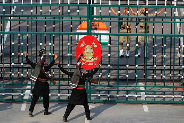 Pakistan's Rangers soldiers, in black, and Indian Border Security Forces soldiers, behind gate, gesture each others during a daily closing ceremony at the Wagah, a joint post on the Pakistan and India border, near Lahore, Pakistan, Monday, May 5, 2025. (AP Photo/K.M. Chaudary)
