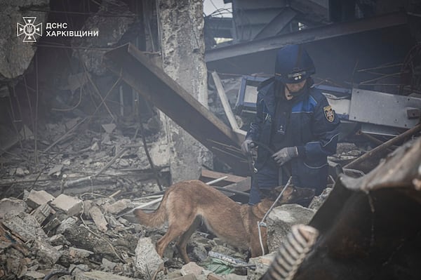 In this photo provided by the Ukrainian Emergency Service, a rescuer and his dog search for victims following a Russian rocket attack in Kharkiv, Ukraine, Tuesday, Tuesday, June 10, 2025. (Ukrainian Emergency Service via AP)