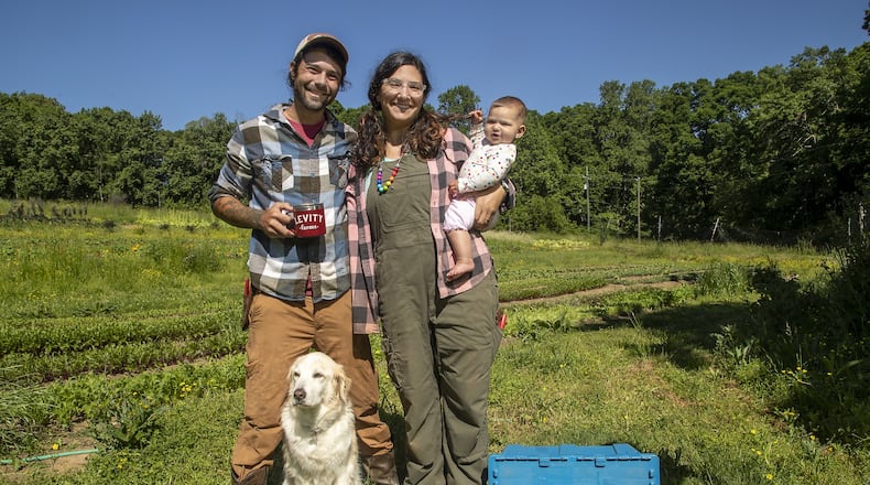Levity Farms owners Zach and Ilana Richards pose for a photo with their 6-month-old daughter Harlyn and their dog Freedom at Levity Farms in Alpharetta. The couple is in the process of moving to a larger property in Madison. ALYSSA POINTER / ALYSSA.POINTER@AJC.COM
