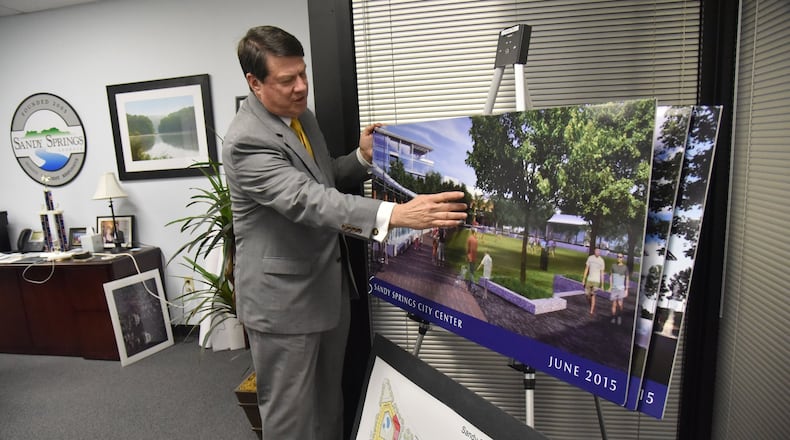 Rusty Paul, mayor of Sandy Springs, shows off concept photographs of new Sandy Springs City Center at his office. For years, the city of Sandy Springs was held up as a model for how to keep government efficient by outsourcing almost all services to private companies. But that model has changed over the years, with the city using more specialized service providers instead of one large private company. HYOSUB SHIN / HSHIN@AJC.COM