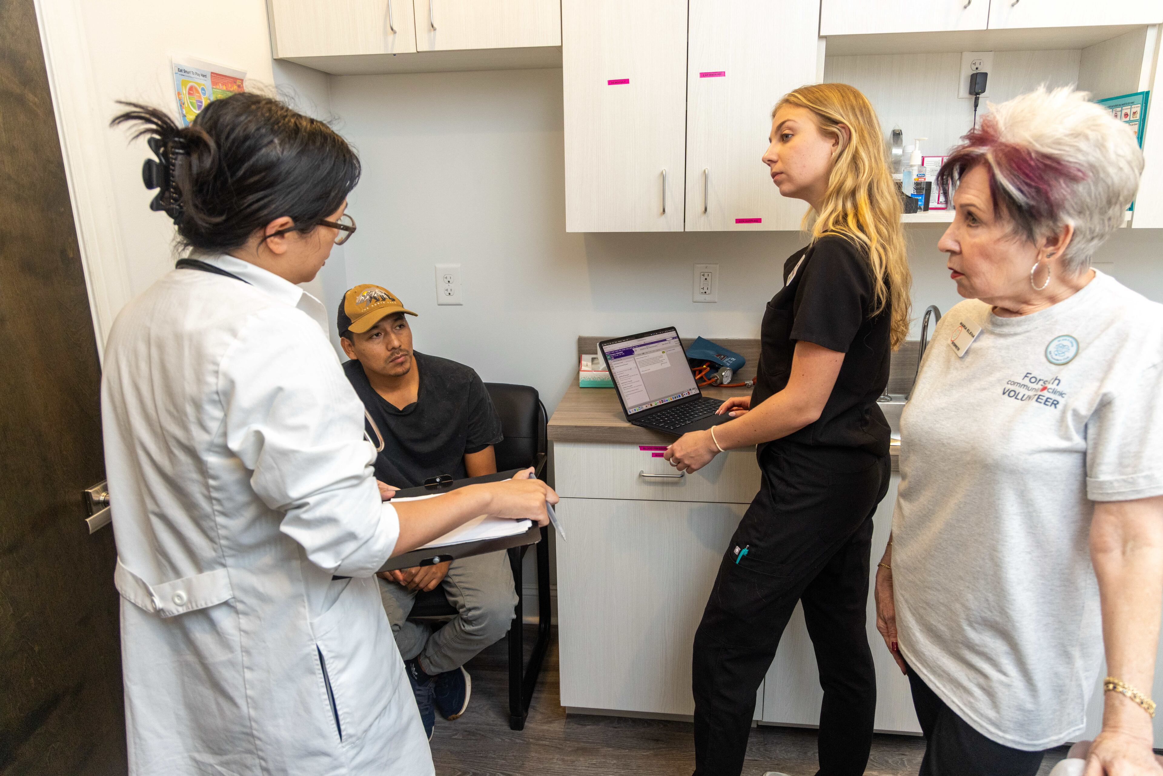 Dr. Zheyu Lu (from left) talks with patient Peregrino Fernandez as medical scribe Sarah Taylor takes notes and Maria Elan interprets during his visit to the clinic. (Phil Skinner for the AJC)