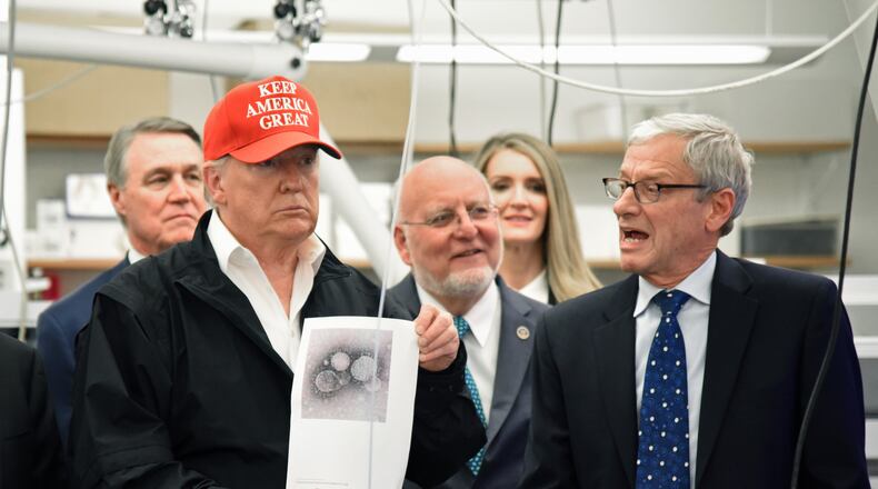 March 6, 2020 Atlanta - President Donald Trump holds a photograph of coronavirus as Dr. Steve Monroe (right) with CDC speaks to members of the press at the headquarters of the Centers for Disease Control and Prevention in Atlanta on Friday, March 6, 2020. President Donald Trump visited the headquarters of the Centers for Disease Control and Prevention in Atlanta on Friday after all, after initially scrapping the trip over concerns that a staffer at the agency had contracted the coronavirus. (Hyosub Shin / Hyosub.Shin@ajc.com)