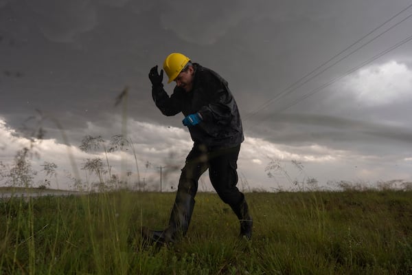 Joey Toniolo ducks from falling hail as he moves back to Northern Illinois University's Husky Hail Hunter vehicle during a Project ICECHIP operation Friday, June 6, 2025, in Morton, Texas. (AP Photo/Carolyn Kaster)