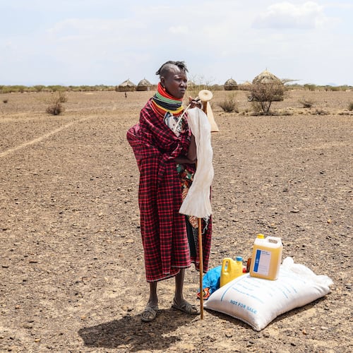 FILE - A woman stands beside her food ration after distribution of aid, in Nalemkais Village, Turkana County, Kenya, Feb. 8, 2026. (AP Photo/Patrick Ngugi, File)