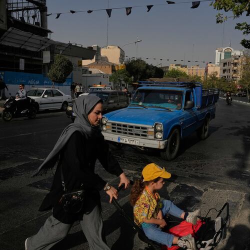 A woman crosses a street with a girl in downtown Tehran, Iran, Wednesday, July 22, 2026. (AP Photo/Vahid Salemi)