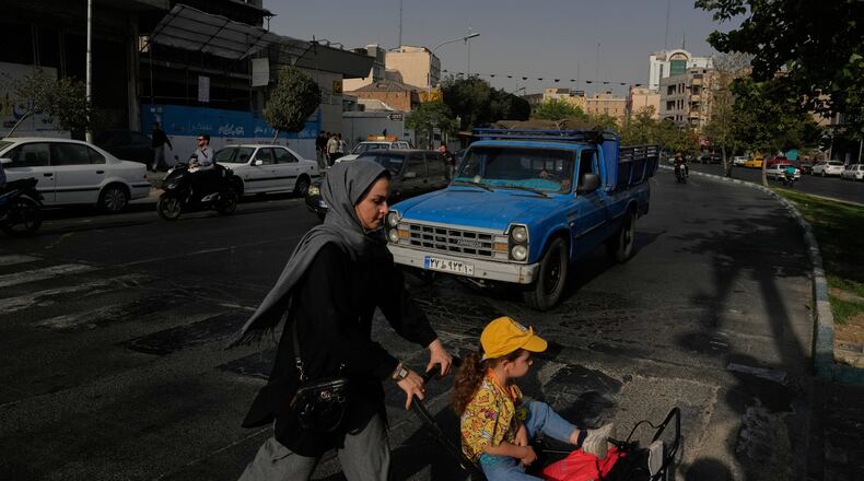 A woman crosses a street with a girl in downtown Tehran, Iran, Wednesday, July 22, 2026. (AP Photo/Vahid Salemi)