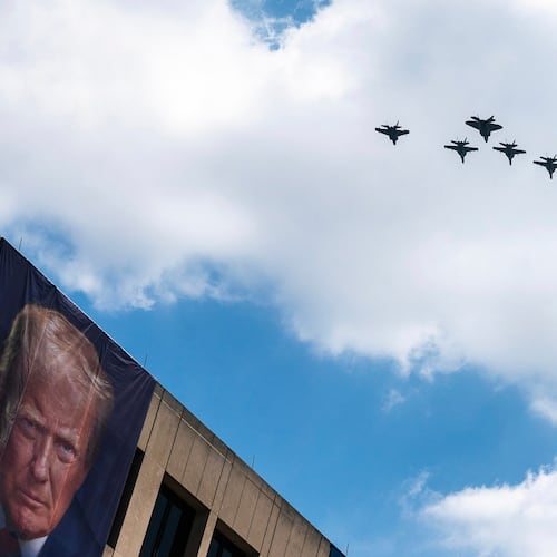 A flight of F-18s, F-35s and a F-22 fly past a picture of President Donald Trump hanging on the U.S. Department of Labor near the Great American State Fair on the National Mall, Friday, July 3, 2026, in Washington. (AP Photo/Nathan Howard)