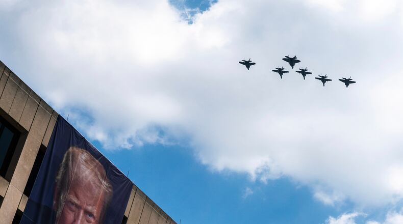A flight of F-18s, F-35s and a F-22 fly past a picture of President Donald Trump hanging on the U.S. Department of Labor near the Great American State Fair on the National Mall, Friday, July 3, 2026, in Washington. (AP Photo/Nathan Howard)