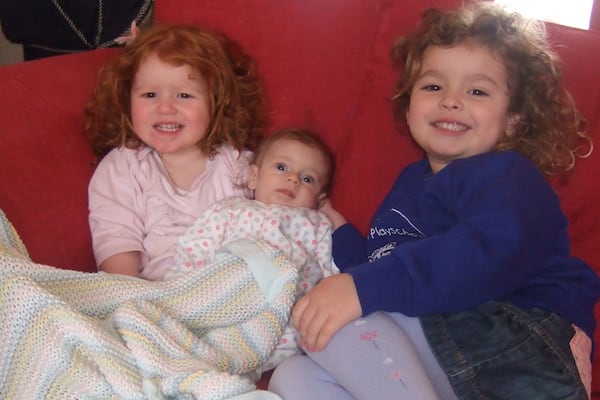 In this photo provided by the Lily Foundation, Rosie and Katie Merritt, of England, hold their sister, Lily, who died of a mitochondrial disease in 2006 at 8-months old. (Lily Foundation via AP)