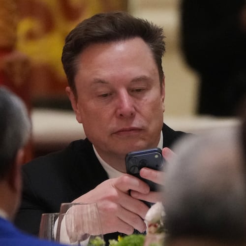 FILE - Elon Musk uses his phone during a state dinner for President Donald Trump and Chinese President Xi Jinping at the Great Hall of the People on Thursday May 14, 2026, in Beijing. (AP Photo/Mark Schiefelbein, File)