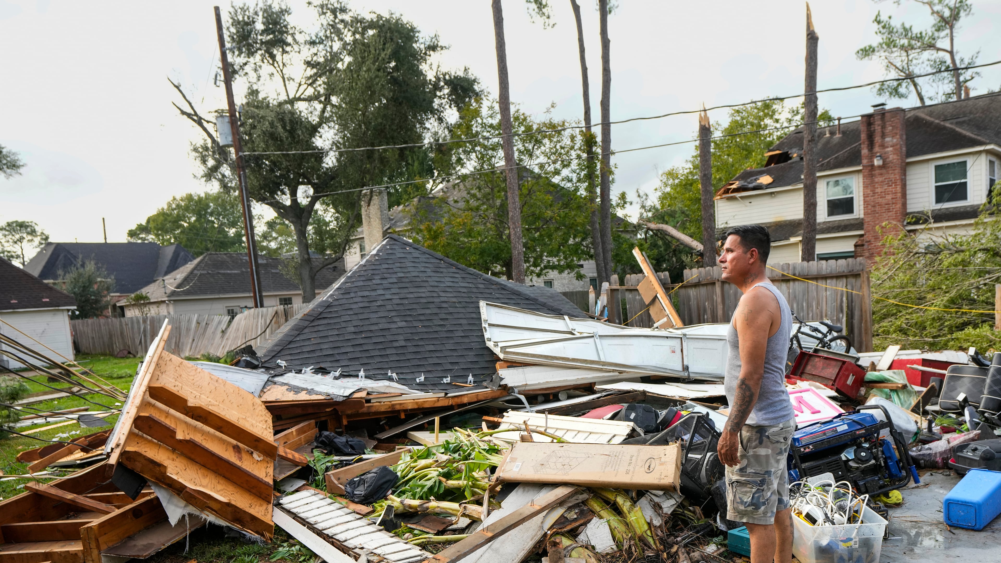 Jose Rosas surveys damage to Guillermo Vargas' home as while helping clean up storm damage in the Memorial Northwest subdivision, in Spring, Texas, Monday, Nov. 24, 2025. (Brett Coomer/Houston Chronicle via AP)