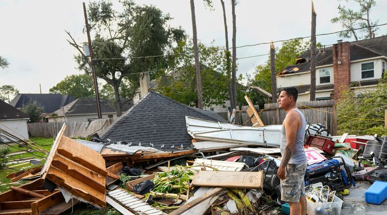 Jose Rosas surveys damage to Guillermo Vargas' home as while helping clean up storm damage in the Memorial Northwest subdivision, in Spring, Texas, Monday, Nov. 24, 2025. (Brett Coomer/Houston Chronicle via AP)