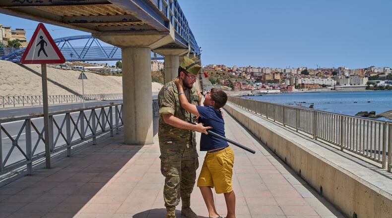 A 12-year-old unaccompanied minor who crossed into Spain is escorted by a Spanish soldier to the Spain-Morocco border as the child begs not to be sent back to Morocco from the Spanish enclave of Ceuta, Monday, Aug. 3, 2026. The forced deportation of the unaccompanied minor was stopped by a high-ranking official a few meters before the child reached the border after residents and journalists said the migrant was a minor. (AP Photo/Bernat Armangue)