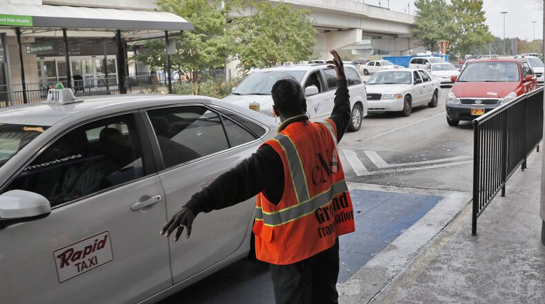 Curbside Management Services employees direct cab drivers and travelers to ground transportation at Hartsfield-Jackson Atlanta International Airport. BOB ANDRES / BANDRES@AJC.COM