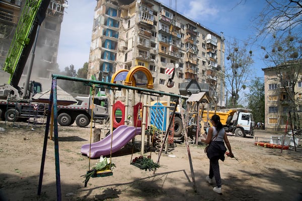 A woman lays flowers at the site of Russia's Tuesday deadly missile attack that ruined a multistory residential building in Kyiv, Ukraine, Wednesday, June 18, 2025. (AP Photo/Efrem Lukatsky)