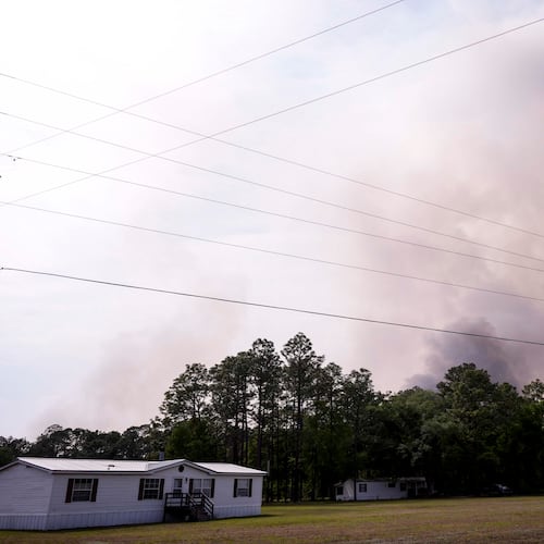 The Pineland road fire in Brantley, county burns behind homes, Wednesday, April 22, 2026, near Nahunta, Ga. (AP Photo/Mike Stewart)
