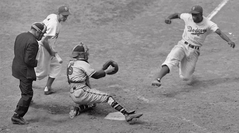 Brooklyn Dodgers’ Jackie Robinson steals home plate successfully as Boston Braves’ catcher Bill Salkeld is thrown off-balance on pitcher Bill Voiselle’s throw to the plate during the fifth inning of a Boston-Brooklyn game at Ebbets Field in New York on Aug. 22, 1948. Third baseman Billy Cox, who was at bat, watches Jackie slide. The umpire is Jocko Conlan. The Braves won 4-3. (AP Photo/Jack Harris)
