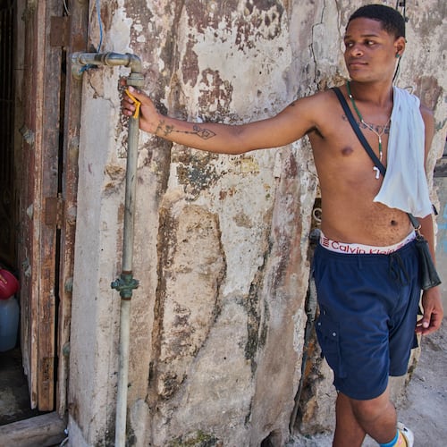 A youth collects water from the bottom floor of a residential building, during a blackout that stopped the water pump, in Havana, Cuba, Tuesday, July 14, 2026. (AP Photo/Ramon Espinosa)
