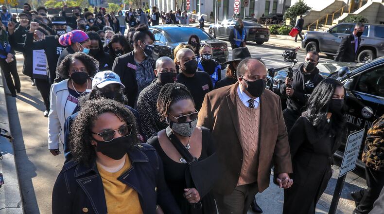 State Rep Park Cannon, second from left, and supporters march silently Monday along Mitchell Street in front of the Georgia Capitol. It was Cannon's return to the Statehouse following her arrest Thursday after knocking on Gov. Brian Kemp’s private office door while he was delivering remarks about the state’s new election overhaul. (John Spink / John.Spink@ajc.com)