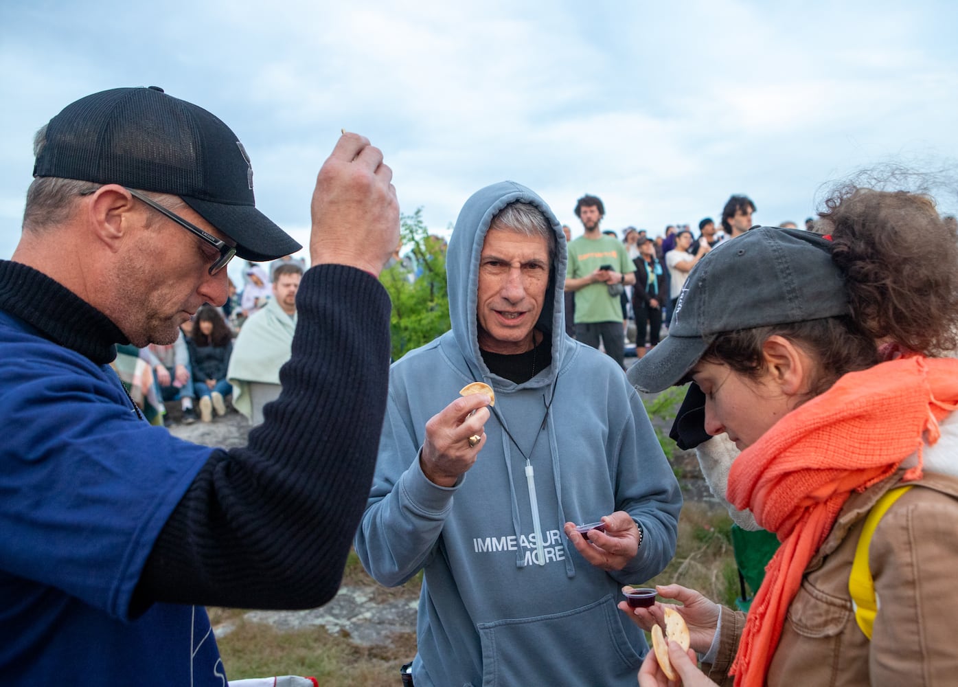Thousands attend Easter sunrise service on top of Stone Mountain on Sunday, April 20, 2025.  Jared Pennisi, from left, Daniel Flagg and Viola Boraros take communion during the program. (Jenni Girtman for The Atlanta Journal-Constitution)