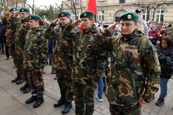 Lithuanian soldiers salute as they come to pay their last respect in memory of three soldiers found dead on Monday at a training range in Pabrade, near the U.S. Embassy in Vilnius, Lithuania, Tuesday, April 1, 2025. (AP Photo/Mindaugas Kulbis)