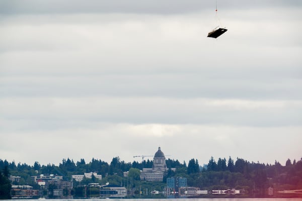 With the Washington Capitol building in the background, an abandoned ship is airlifted on Wednesday, June 4, 2025, in Olympia, Wash. (AP Photo/Jenny Kane)