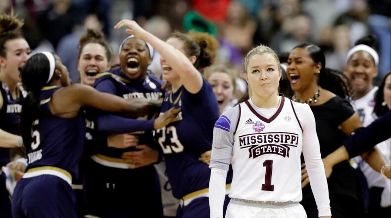 Notre Dame's Arike Ogunbowale is congratulated by teammates as Mississippi State's Blair Schaefer (1) walks away after Ogunbowale made a 3-point basket to defeat Mississippi State 61-58 in the final of the women's NCAA Final Four college basketball tournament, Sunday, April 1, 2018, in Columbus, Ohio. (AP Photo/Tony Dejak)