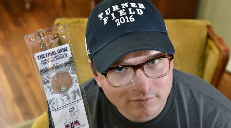 Justin Green, disgruntled Braves fan, holds the final game ticket from Turner Field at his home on Thursday. Green will be going to the game Sunday with his “Turner Field 2016” hat on in silent protest of the move. HYOSUB SHIN / HSHIN@AJC.COM