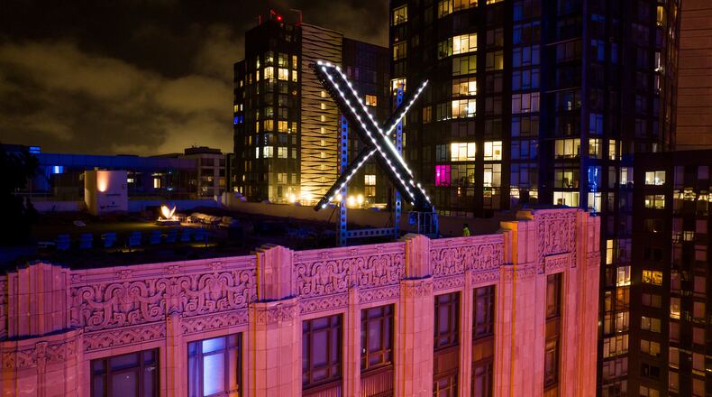 FILE - Workers install lighting on an "X" sign atop the company headquarters in downtown San Francisco, July 28, 2023. (AP Photo/Noah Berger, File)