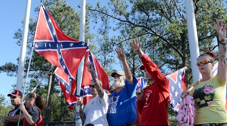 Pro-Confederate flag supporters at a protest at Stone Mountain last November offer a Klan “salute” at the base of the mountain trail. Organizers for the rally initially denied connections to white extremists, but photos posted later to social media showed them in clothing with Klan symbols. KENT D. JOHNSON / KDJOHNSON@AJC.COM