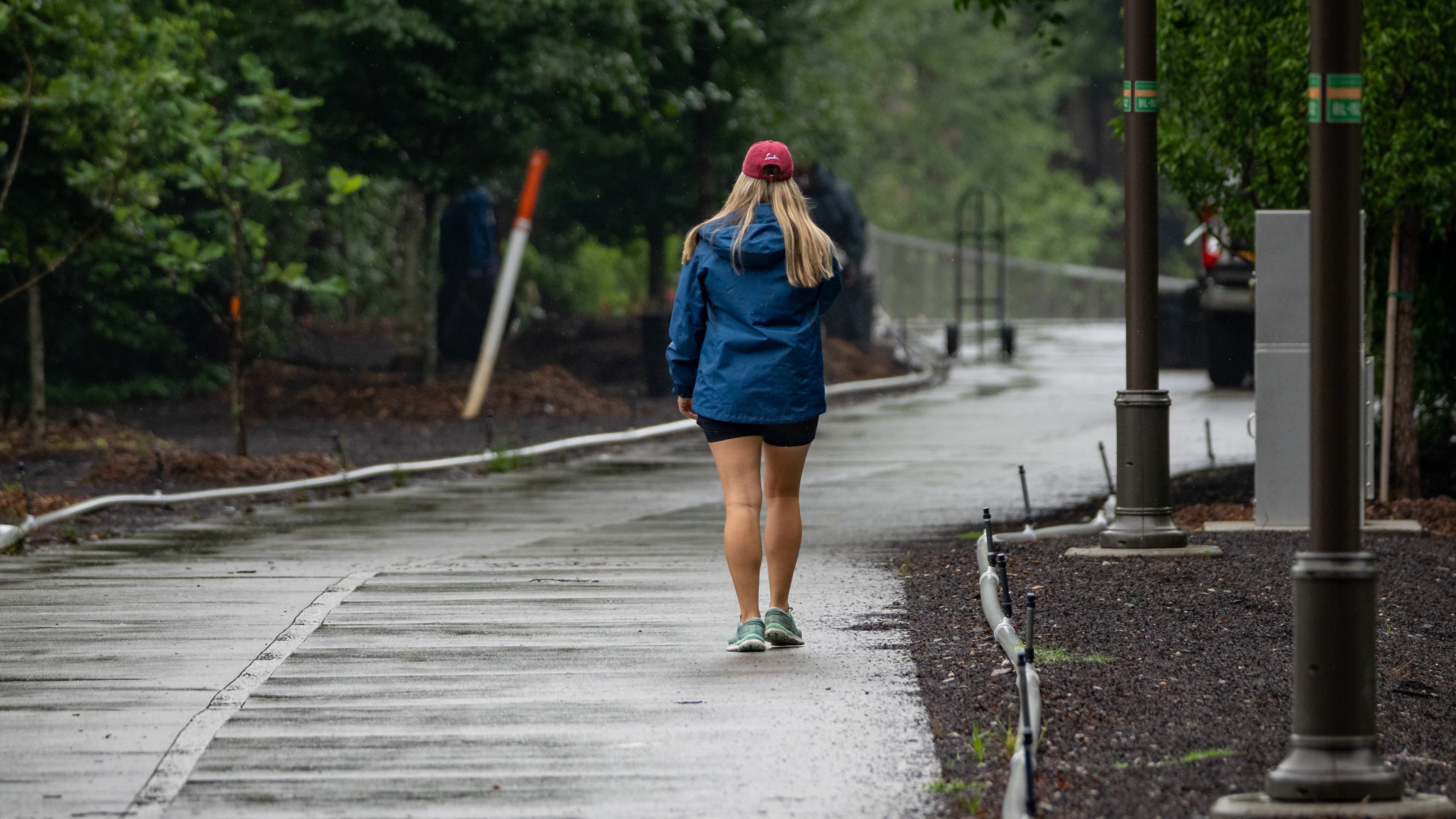 A woman walks down the Beltline near Piedmont Park as rain fell steadily throughout the day. (Ben Hendren for the AJC)