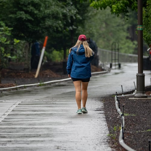 A woman walks down the Beltline near Piedmont Park as rain fell steadily throughout the day. (Ben Hendren for the AJC)
