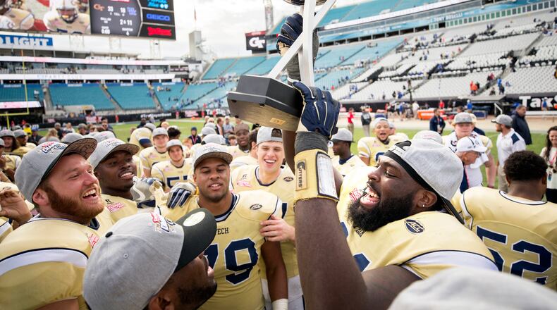 Georgia Tech defensive lineman Patrick Gamble (91) and his team mates celebrate with the trophy after the TaxSlayer Bowl NCAA college football game against Kentucky, Saturday, Dec. 31, 2016, in Jacksonville, Fla. Georgia Tech beat Kentucky 33-18. (AP Photo/Stephen B. Morton)